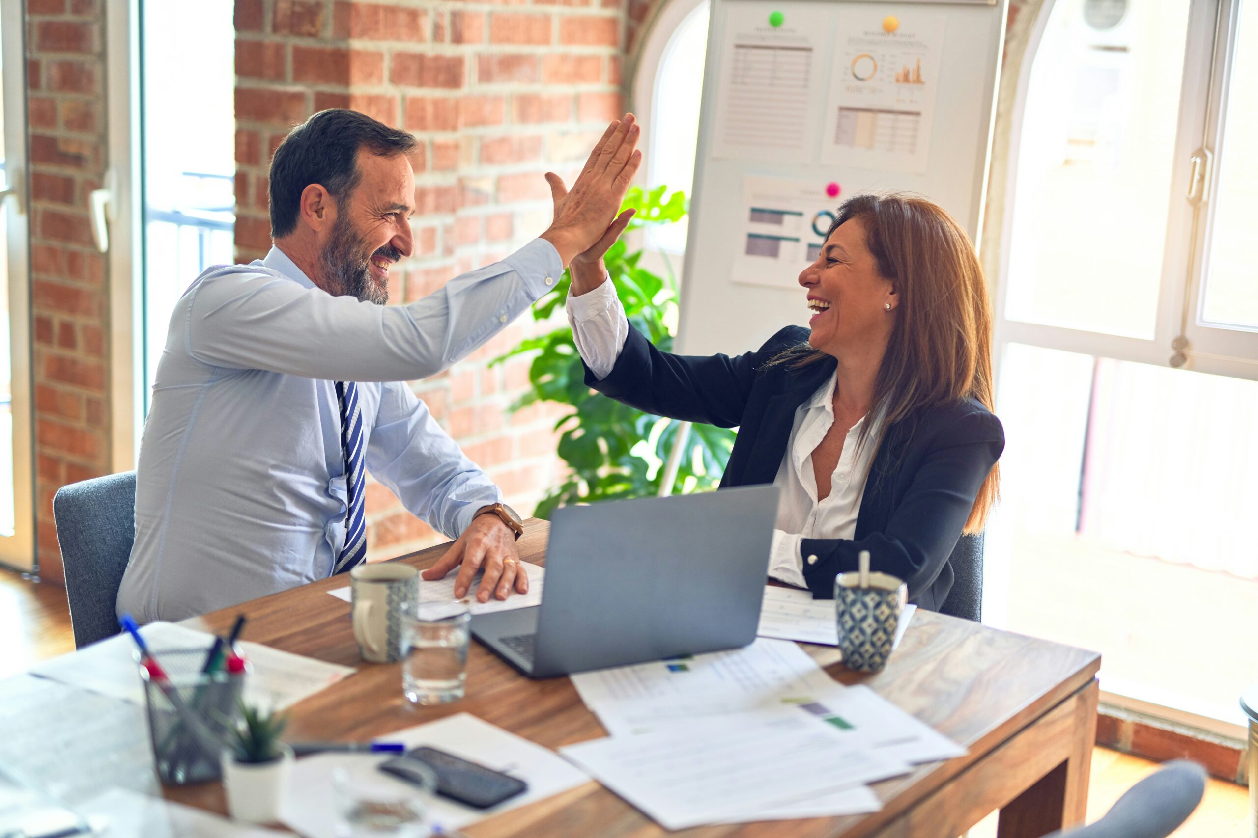 Two people high-fiving in office.